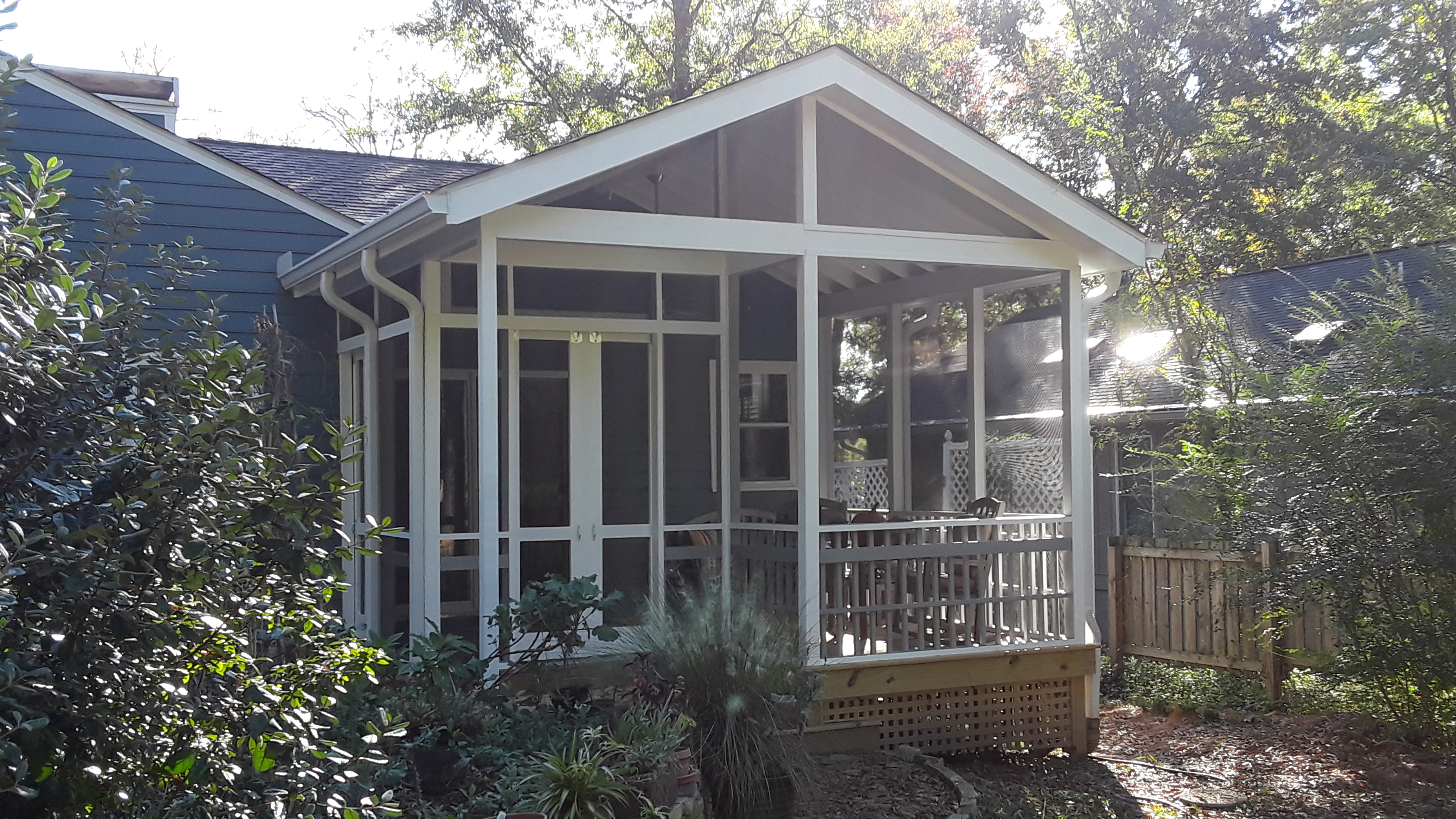 A screened-in porch with sliding doors. as an entrance on its left and seating on the right.